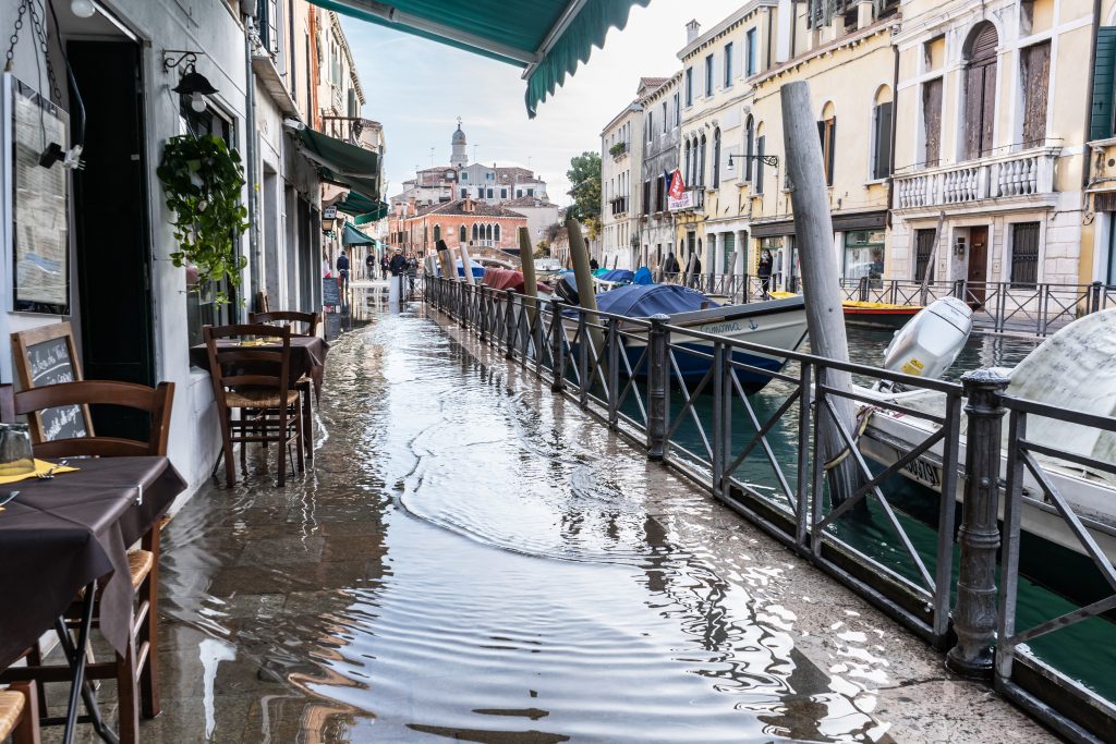 A canal which is flooding slightly above street level into the nearby restaurants in Venice